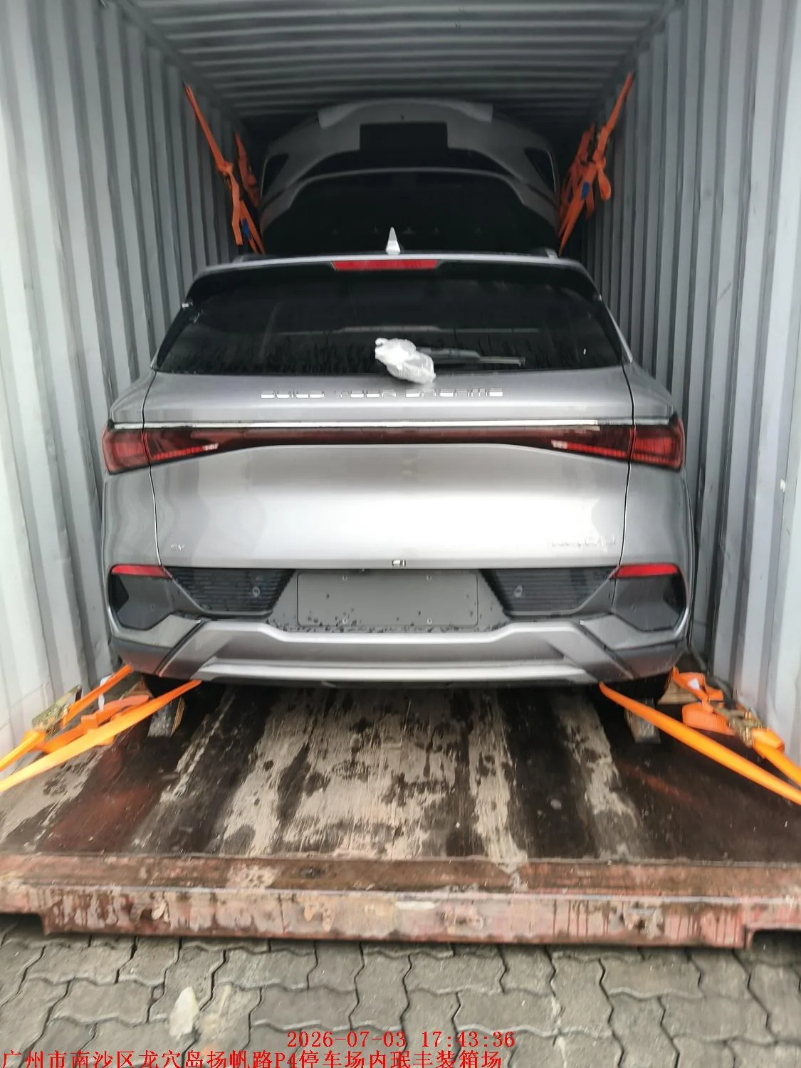 Vehicle secured with orange cargo straps inside an export container